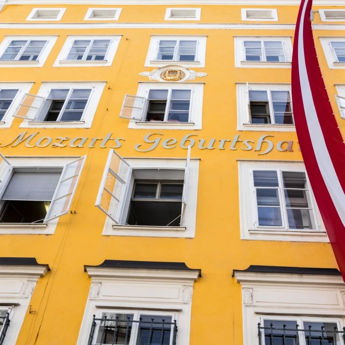 This image shows Mozart's Birthplace in Salzburg, Austria, a bright yellow historic building marked with the words 
