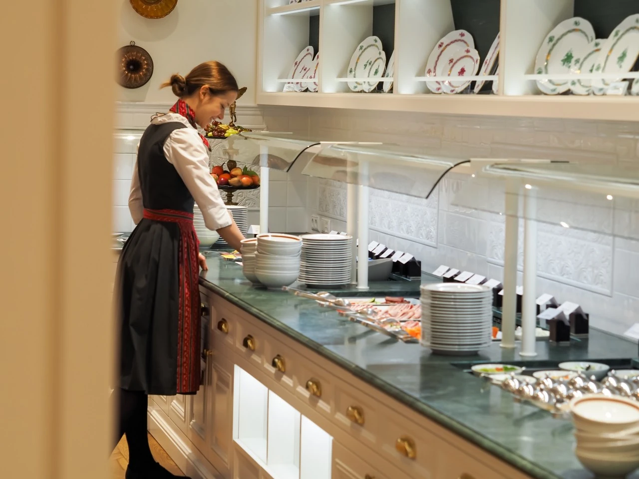 This image beautifully captures the refined breakfast service at Hotel Sacher Salzburg, showcasing a traditional setting with elegant tableware, a carefully curated buffet, and staff dressed in authentic attire—reflecting the hotel's dedication to timeless Austrian hospitality.