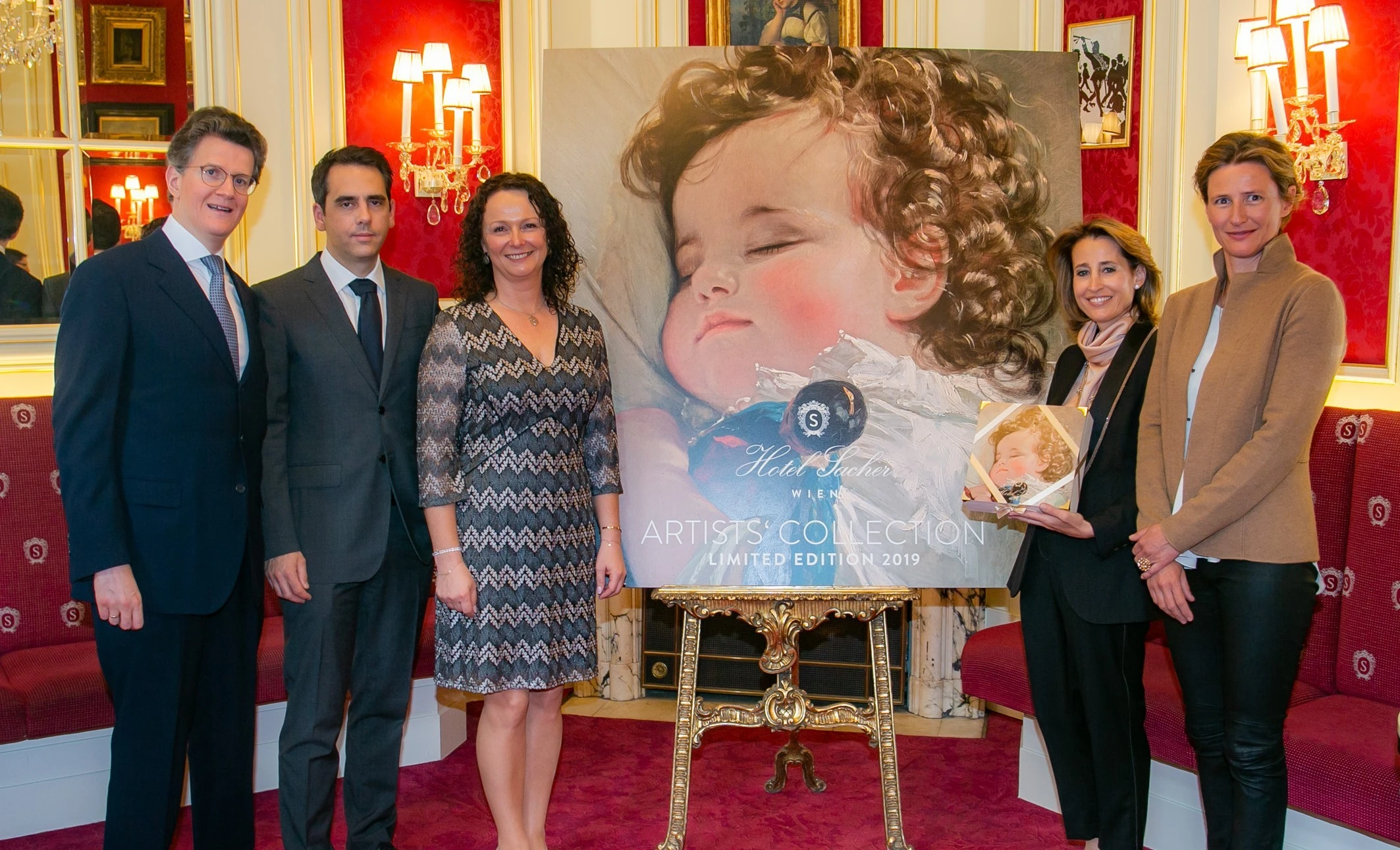 The image shows (from left to right) Georg Gürtler, BA (Owner, Sacher Hotels), Assoc. Prof. PD. Dr. Daniel Zimpfer (Head Senior Consultant, Pediatric Cardiac Surgery), Michaela Altendorfer (President, Herzkinder Österreich), H.S.H. Princess Marie of Liechtenstein, and Mag. Alexandra Winkler (Owner, Sacher Hotels), standing in front of the 2019 *Artists’ Collection* limited edition artwork at Hotel Sacher, featuring a tender painting of a sleeping child.